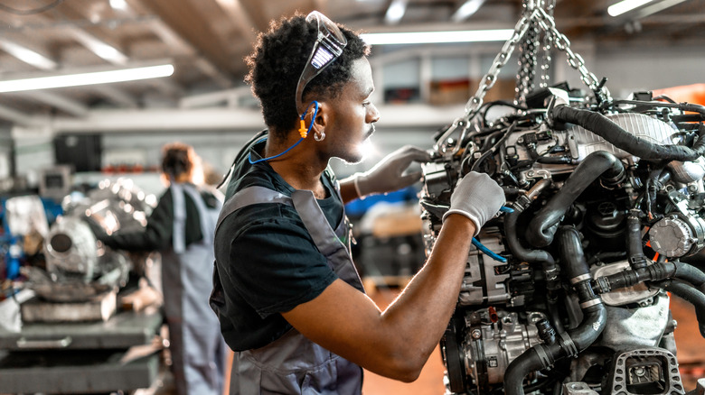 A mechanic working on an engine on a hoist