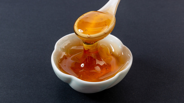 A small bowl of sticky maltose syrup being ladled with spoon.
