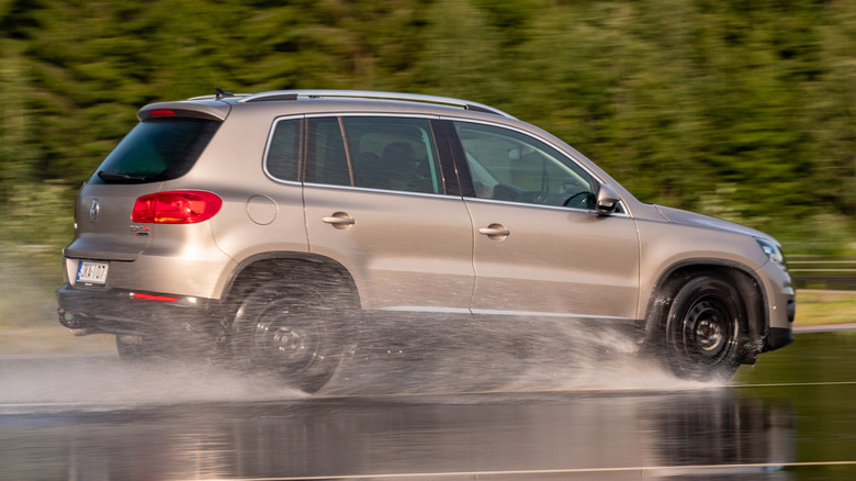 A gold Volkswagen Tiguan braking on a wet road on a proving ground during tire tests.