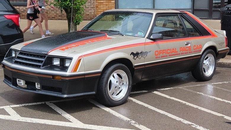 A 1979 Ford Mustang Indy 500 Pace Car replica parked a car show during a rainy day