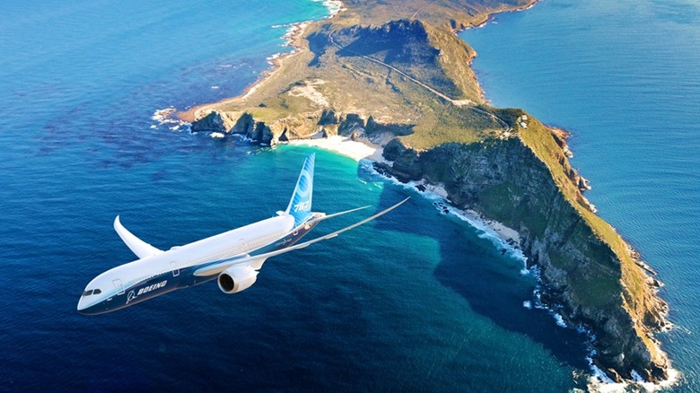 Boeing 787 aircraft in flight over an island