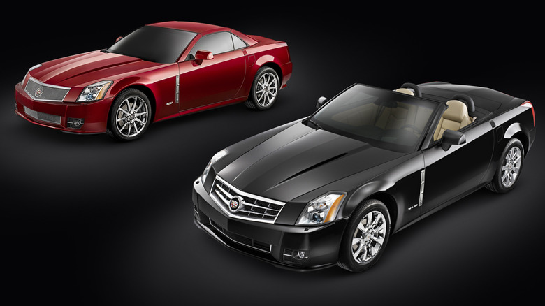 a red XLR-V with its top up parked next to a black XLR with its top down in front of a black background