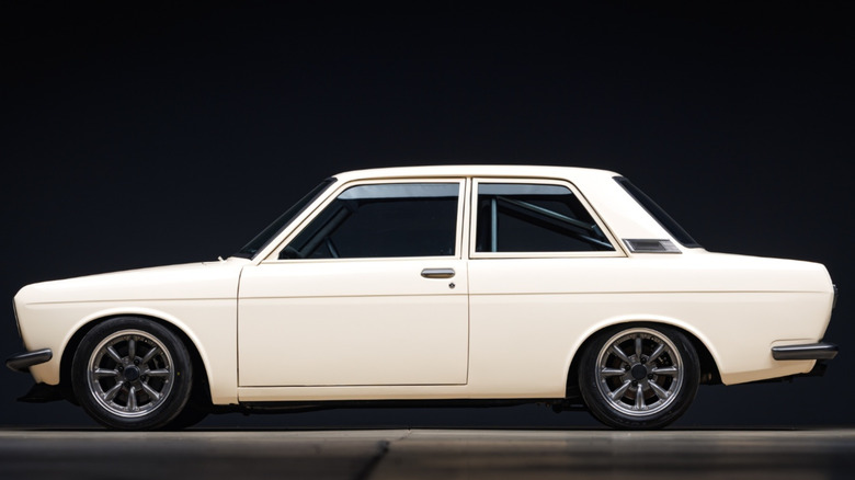 A white 1971 Datsun 510 two-door in front of a black background