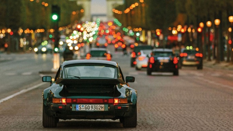 A Porsche 930 driving through Paris with heavy traffic ahead of it