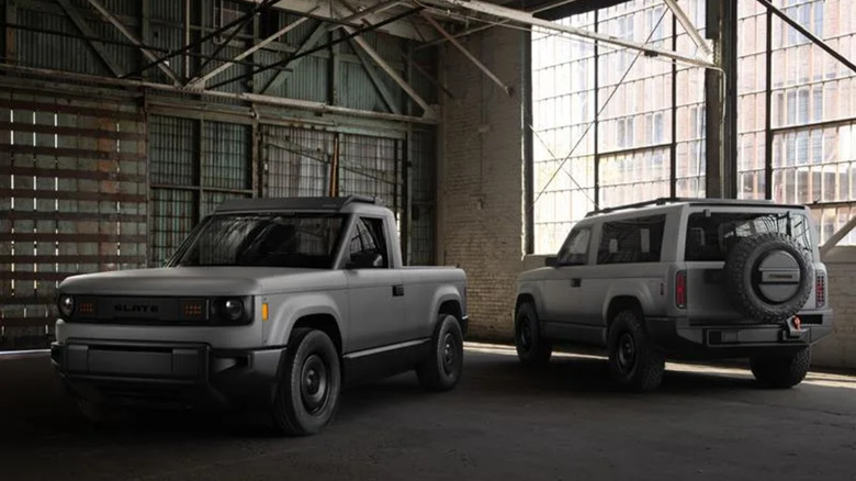 Two Slate trucks (one with a bed and one with an SUV topper) parked in an empty warehouse