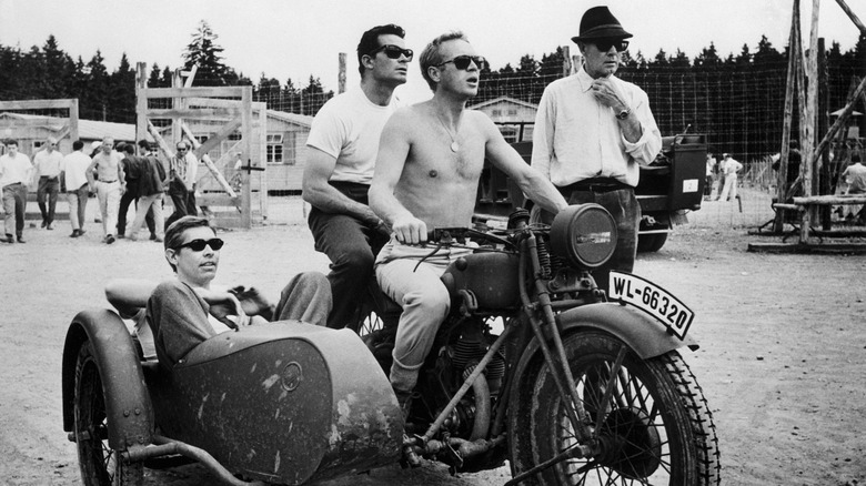 Steve McQueen, James Garner, and James Coburn pile onto a motorcycle and sidecar on the set of 'The Great Escape'