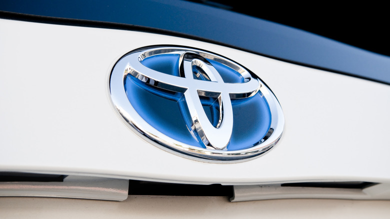 The bluish Toyota badge on a Toyota hybrid car