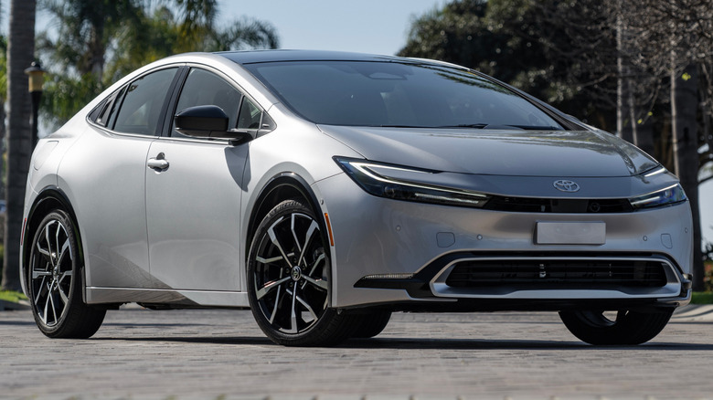 A 2025 Toyota Prius PHEV XSE parked on a paved surface with trees in the background