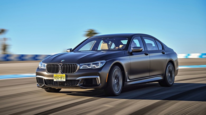 front three-quarters shot of a matte black BMW M760Li driving around a corner on a track