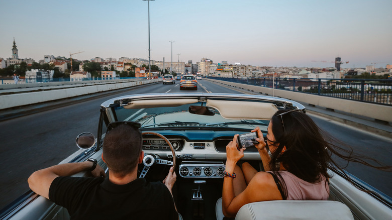 Two people driving a vintage convertible in the city