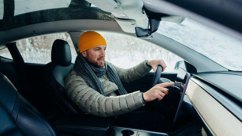Driver adjusting settings on infotainment screen while driving