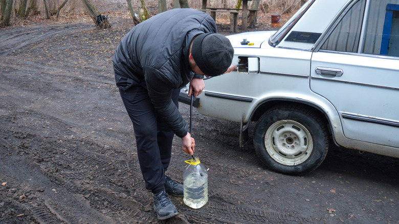 A person siphoning fuel from a car