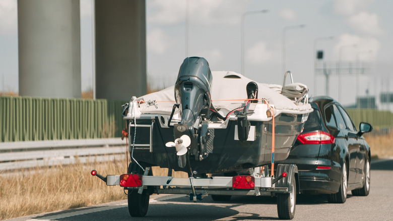 A car towing a motor boat with an outboard motor