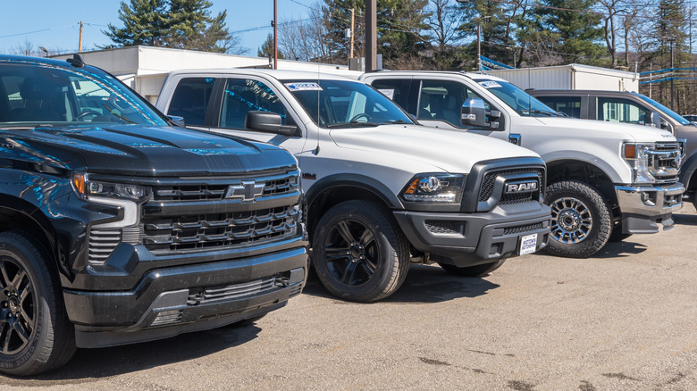 A line of pickup trucks parked outside of a dealership