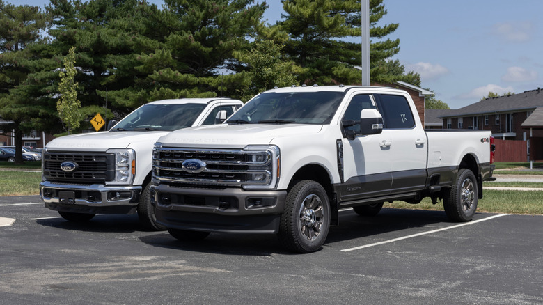 Two white pickup trucks parked in a parking lot
