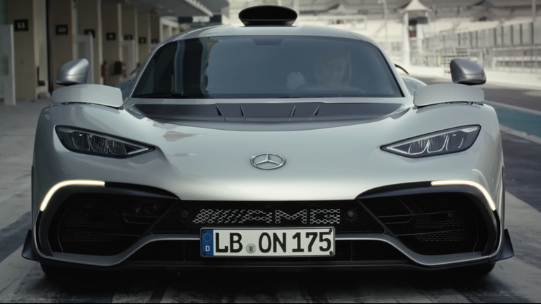 A front-end view of a Mercedes AMG ONE hypercar on a track.