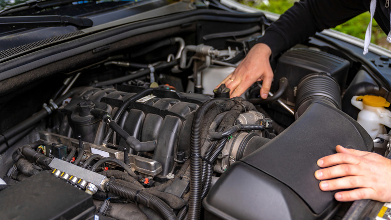 A person performing work on a car's engine.