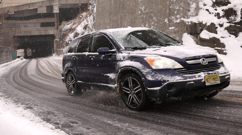 A black Honda crossover driving on a steep road with snow and ice