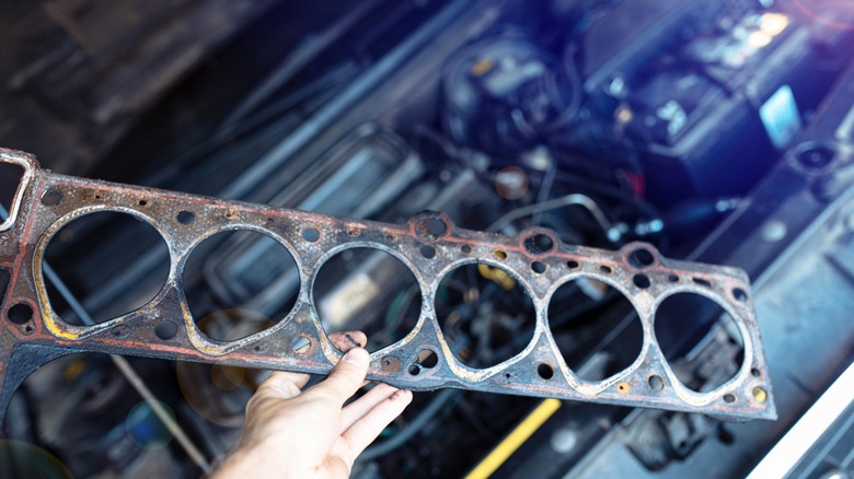 A mechanic holding a used head gasket.