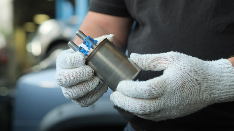 A mechanic holding a fuel pump and filter assembly