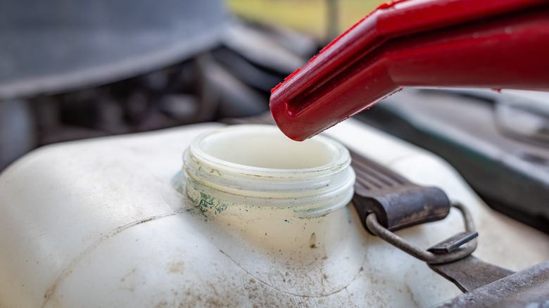 A red nozzle above an open windshield wiper fluid reservoir.
