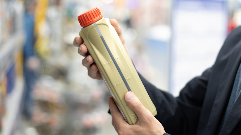 A container of motor oil being held by a person