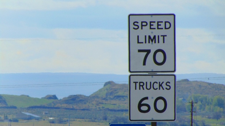 A differential speed limit sign with speed limit 70 and trucks 60 with the backdrop of a mountainous valley.
