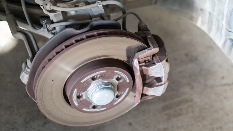 Car brake rotor and caliper in a workshop with the wheel removed