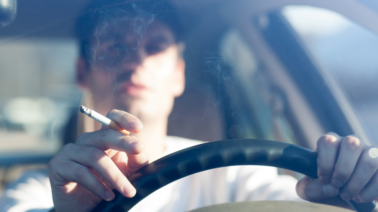 A younger male smoking while driving.
