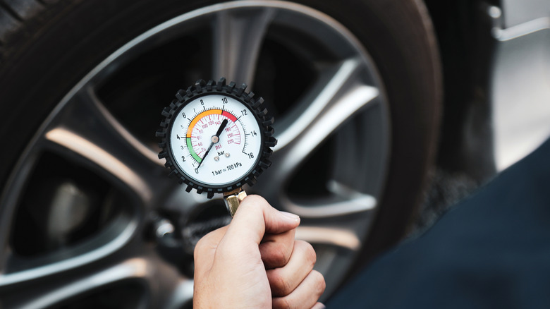 Car mechanic holding equipment to check tire pressure