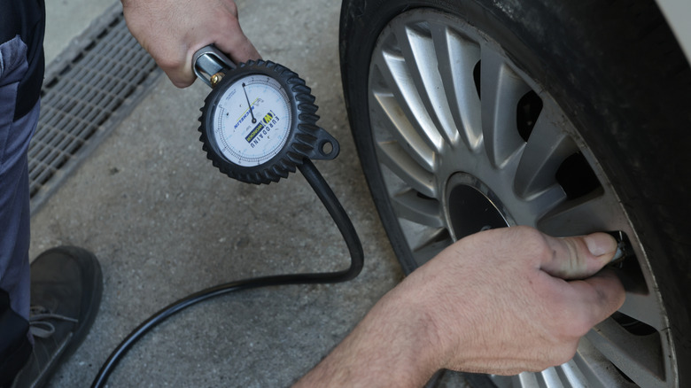 A man inflates a car tire to the proper PSI.