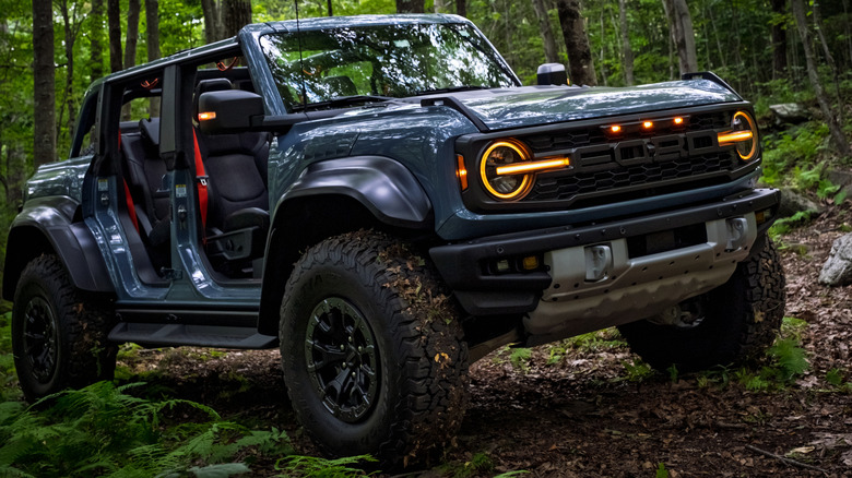 Blue Ford Bronco Raptor with doors and roof off in the woods