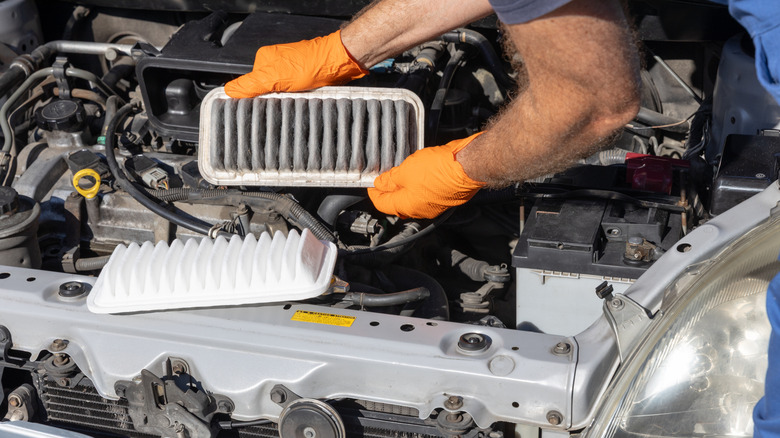 Stock image of a mechanical replacing a car's air filter.