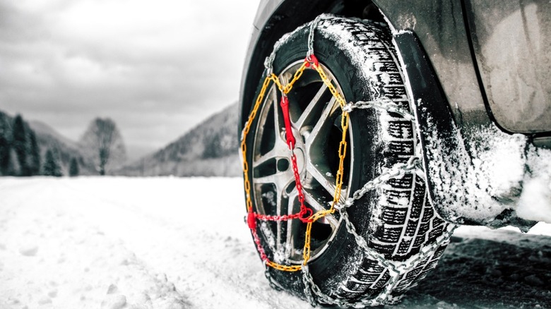 Tire chains on tire of car on snowy road