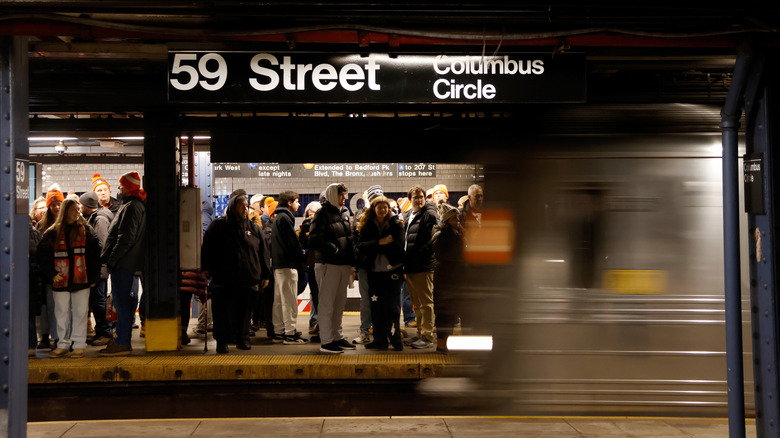 NEW YORK, NY - DECEMBER 27: People wait to board an orange-line train at the 59th Street - Columbus Circle subway station on December 27, 2025, in New York City. (Photo by Gary Hershorn/Getty Images)