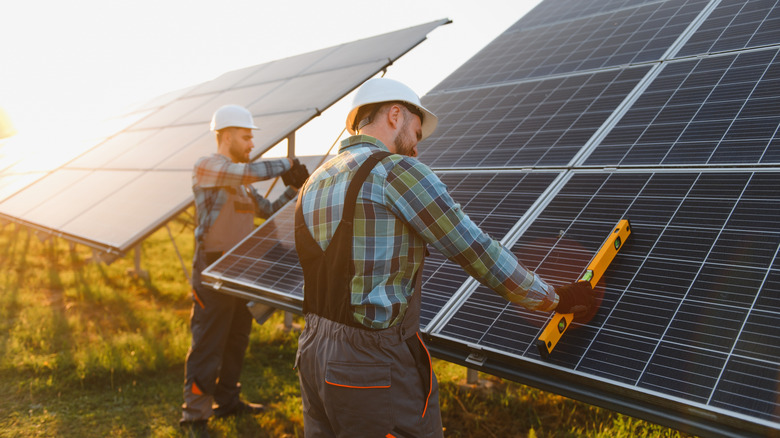 Workers install utility-scale solar panels at a solar farm