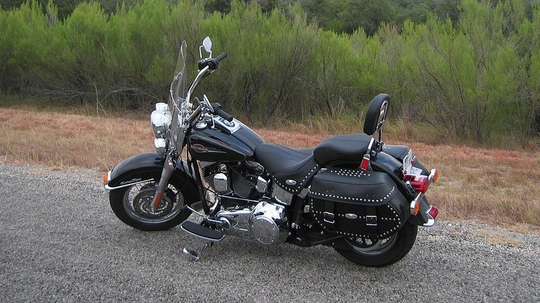 A Harley Davidson Heritage Softail Classic sits on a gravel road.