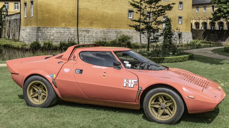 An orange Lancia Stratos parked on the grass