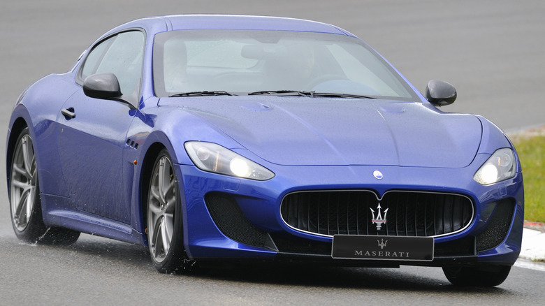 A blue Maserati GranTurismo driving on a wet track