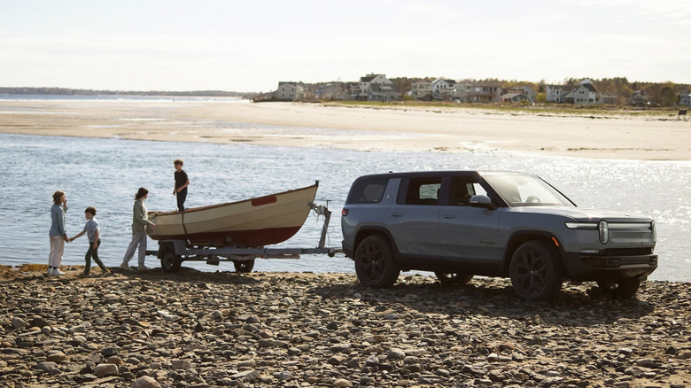 2026 Rivian R1S at a beach with a family and a boat on a trailer