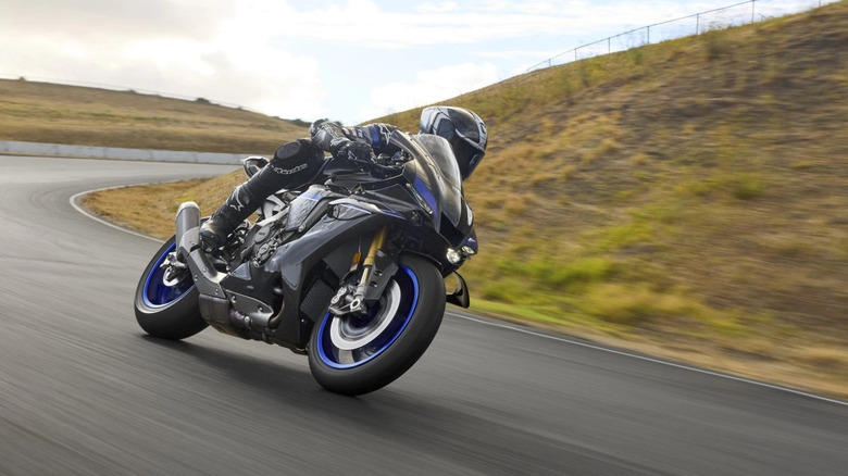 Yamaha YZF-R1M with rider cornering at speed front 3/4 view