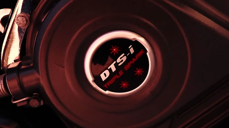 A closeup of the Bajaj DTS-i Triple Spark logo on a Pulsar NS200 motorcycle