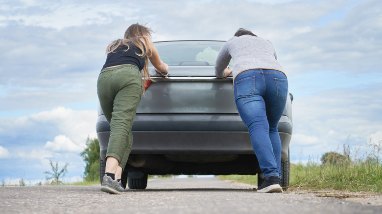 Two young women pushing a car