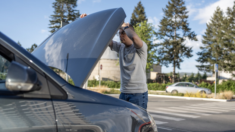Man lifting nan hood inspect nan motor bay