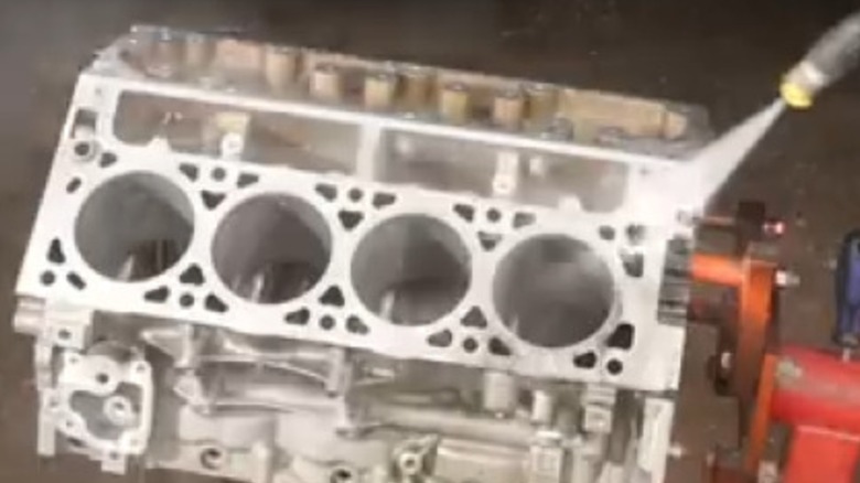 An engine block being cleaned with a pressure washer.