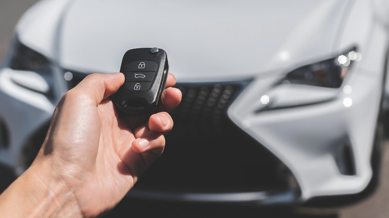A person preparing to use a key fob near their vehicle