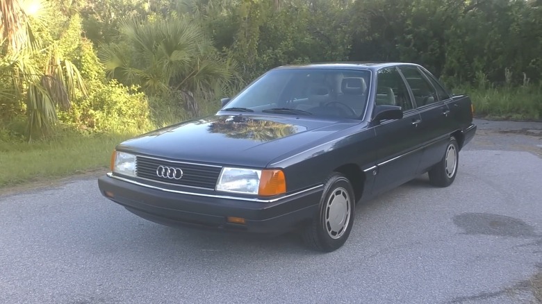 An 80's Audi 5000 parked near grass and trees