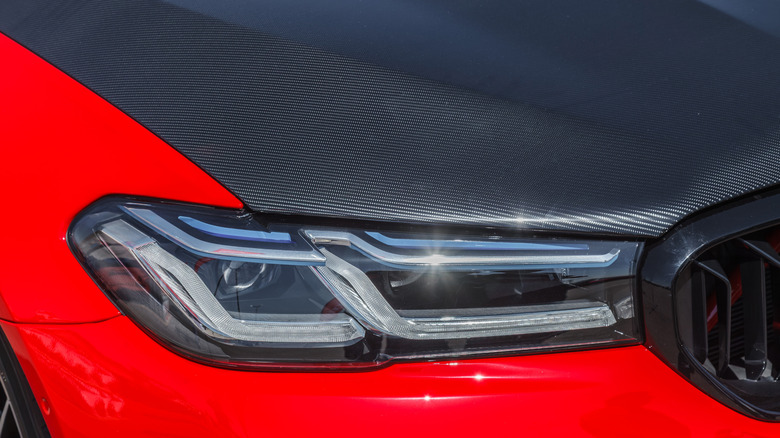 A closer front view of a red BMW sedan with a sporty carbon fiber hood
