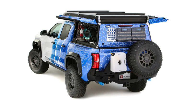 A blue and white Toyota Tacoma pickup truck, with overland kit attached