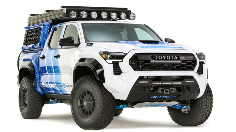 A blue and white Toyota Tacoma pickup truck, with overland kit attached